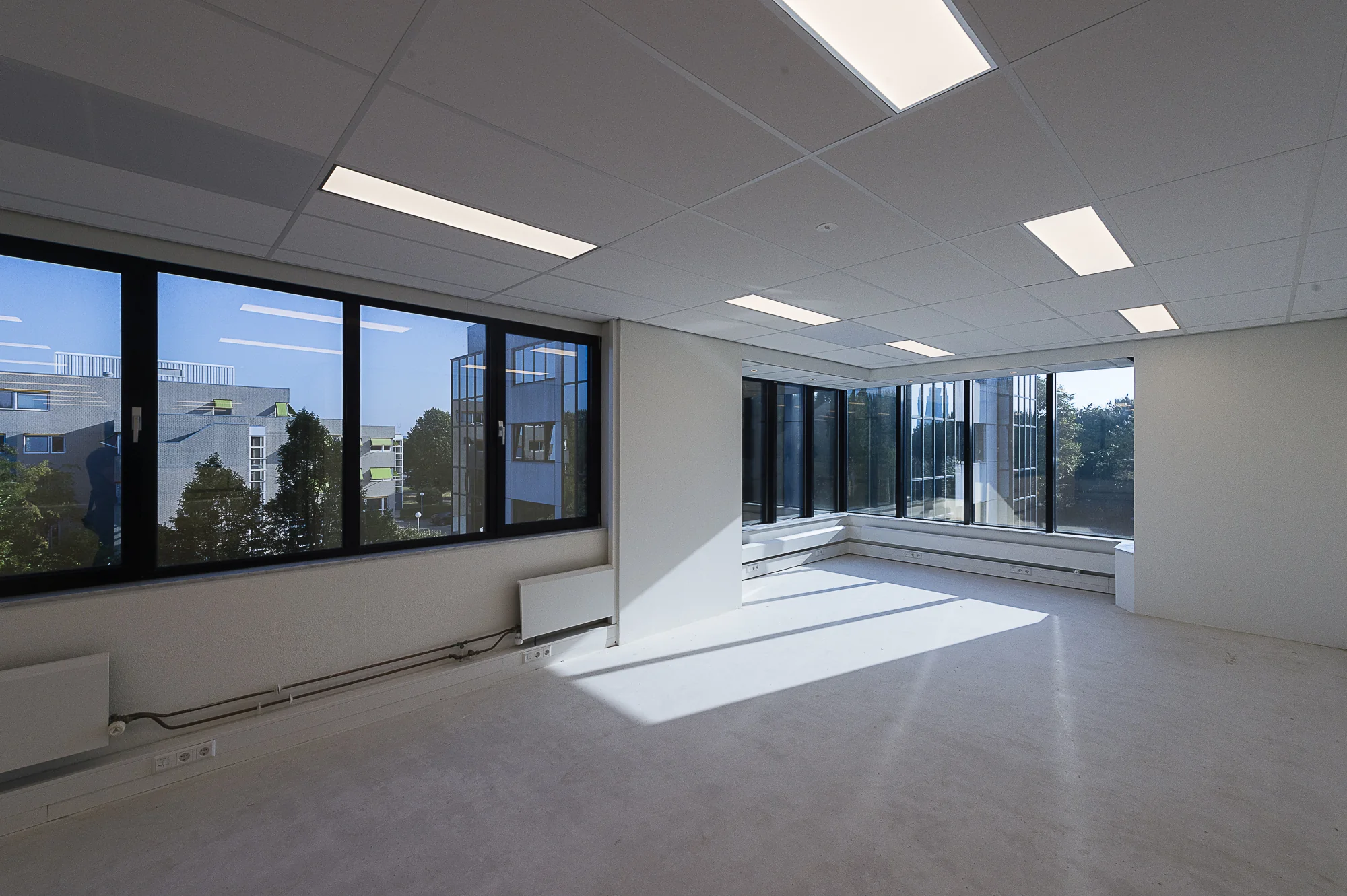 Lichte, lege kantoorruimte met grote ramen aan de Max Euwelaan.